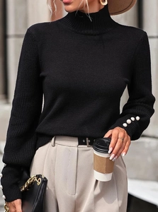 Close-up of black ribbed knit sweater featuring elegant white pearl buttons on the cuffs