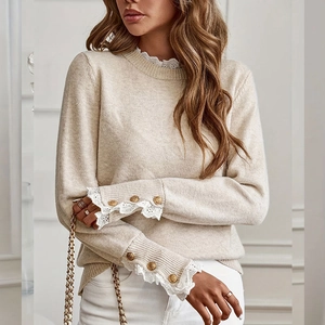 Close-up of cream knit sweater with lace neckline and gold buttons on sleeve cuffs