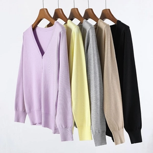 Detail view of multi-color V-neck knit cardigans with ribbed cuffs on wooden hangers