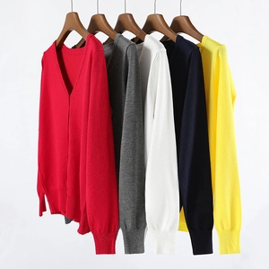 Detail of V-neck knitted cardigans in multiple colors hanging on wooden hangers
