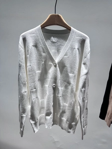 Detailed view of white V-neck knit cardigan featuring textured jacquard and matching buttons