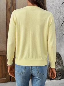 Rear view of light yellow knit cardigan featuring ribbed cuffs and relaxed fit