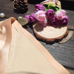 Gros plan sur la texture du tissu soyeux beige sans couture sur fond de bois sombre