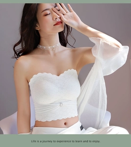 Detail of white lace tube top with scalloped edges and center rhinestone decoration