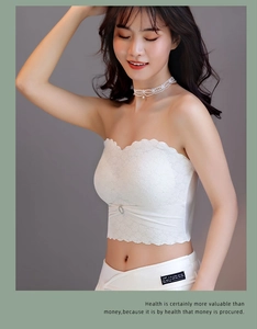 Detail of white strapless lace bra featuring floral patterns and a centered rhinestone button