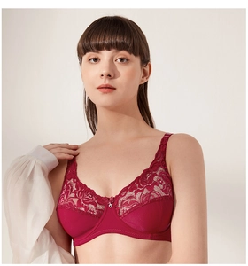 Detail of burgundy lace bra with floral patterns and a small silver heart pendant