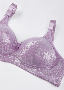 Detailansicht eines lila Spitzen-BHs mit floralem Muster, kleiner Schleife und Trägern