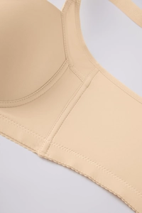 Macro shot of seamless nude bra showing wide side wings and scalloped hemline detail