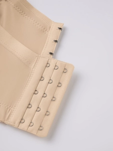 Detailed macro view of beige bra with four-row metal hook and eye closure and neat stitching