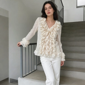 Close-up of the ruffled V-neckline and intricate floral lace texture of this cream blouse