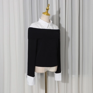 Dettaglio del maglione a strati bianco e nero con design a finto due pezzi su un manichino