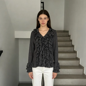 Detail of dark grey ruffled blouse with pleated texture and elegant v-neck design