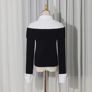 Dettaglio di un elegante top nero con colletto bianco e polsini bianchi a contrasto