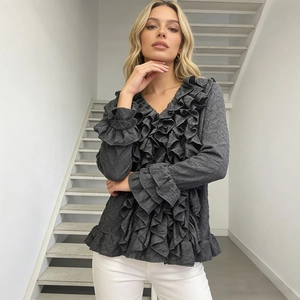 Detailed view of layered ruffles on cuffs and neckline of this dark grey textured shirt