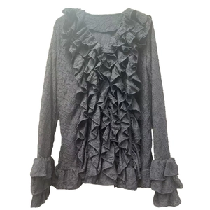 Detailed view of layered ruffles and crinkled texture on a black long-sleeve blouse