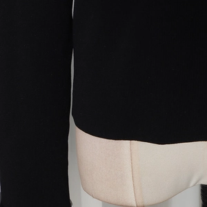 Dettaglio della trama a maglia fine e delle cuciture di un maglione nero a maniche lunghe
