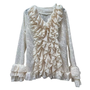 Detail of delicate lace fabric and multi-layered ruffled collar on cream blouse