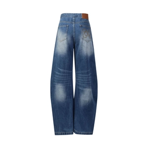 Dettaglio dei jeans blu a gamba dritta con ricamo dorato e salpa in pelle marrone