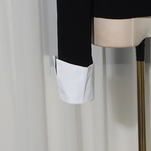 Dettaglio maglione maniche lunghe con polsini a contrasto bianchi e tessuto nero elegante