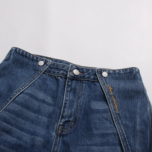 Dettaglio vita in denim blu con design a doppio strato, bottoni in metallo e ricamo oro