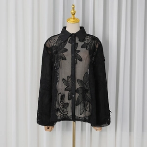 Vue détaillée du chemisier noir en résille transparente avec broderie florale élégante