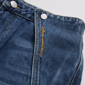 Dettaglio della vita in denim con bottone in metallo e ricamo di lettere personalizzato