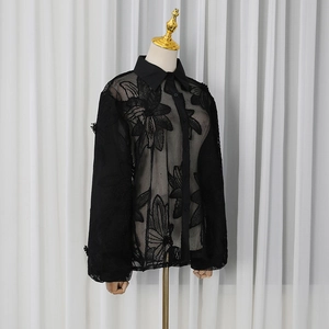 Détail de la chemise noire transparente en tulle avec appliques florales et col classique