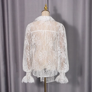 Détail de chemise en dentelle blanche montrant la texture florale au dos et les poignets