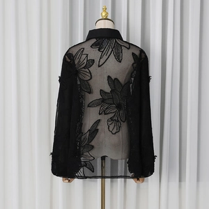 Détail d'une chemise en maille noire avec broderie florale et col classique élégant