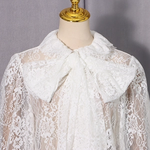 Détail de chemise en dentelle florale blanche avec un grand nœud décoratif au col