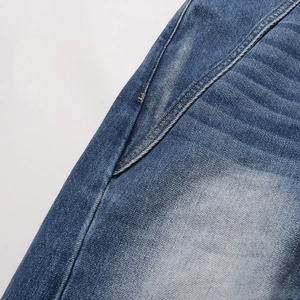 Dettaglio del tessuto denim blu lavato, focus sulla tasca laterale e cuciture precise