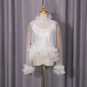 Detail of white mesh blouse with ruffled edges and inner camisole shown on a mannequin