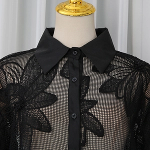 Détail de la chemise en résille noire avec broderie florale complexe sur un mannequin de couture