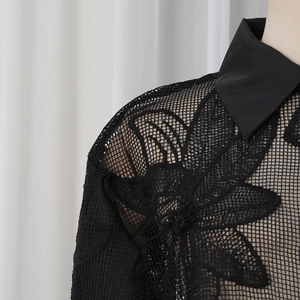 Gros plan détaillé de la broderie florale sur dentelle en maille noire pour chemisier