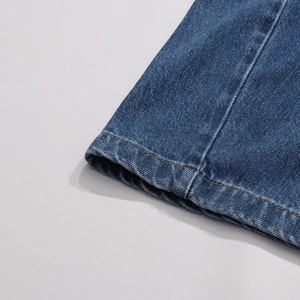 Dettaglio ravvicinato dell'orlo in denim blu con cuciture a contrasto arancioni