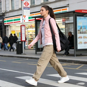 Detail of pink quilted down jacket with white inner top and khaki cargo pants street style