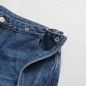 Dettaglio di jeans a vita alta con doppi bottoni automatici in metallo e cuciture gialle