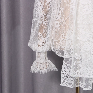 Détail de la manche en dentelle blanche avec poignets volantés et texture florale