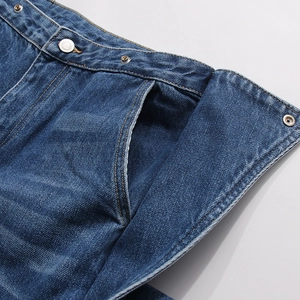 Dettaglio jeans blu scuro con bottoni in metallo e cuciture arancioni a contrasto