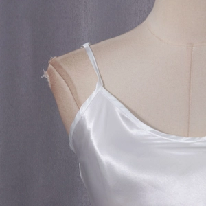 Close-up of white silk satin camisole with thin straps and smooth glossy texture