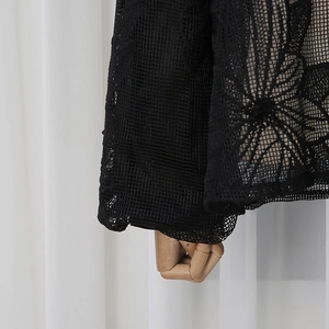 Détail de la manche en résille noire avec broderies florales élégantes et texture de dentelle