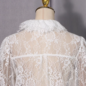 Détail du dos d'un chemisier blanc en dentelle avec des motifs floraux délicats
