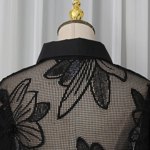 Détail d'une chemise élégante en résille noire avec broderie florale complexe sur le dos