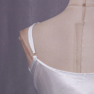 Detail of adjustable shoulder strap and glossy white satin fabric on a women's camisole