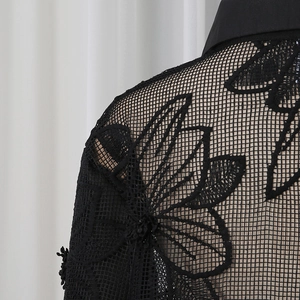 Gros plan sur le tissu en dentelle noire avec broderies florales sur la zone de l'épaule