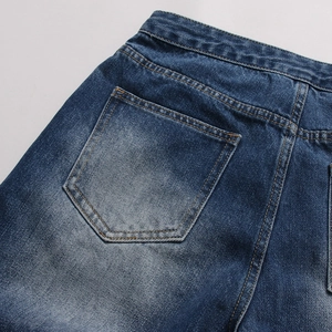 Dettaglio di jeans blu scuro con lavaggio intenso e cuciture a contrasto arancioni rifinite
