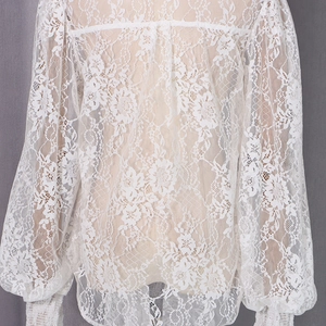 Détail de la blouse blanche en dentelle à manches longues avec broderie florale délicate