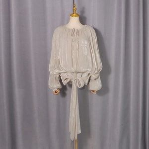 Detail of elegant champagne pleated blouse with a large bow and lantern sleeves