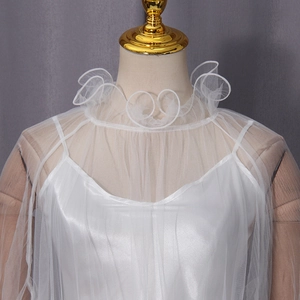 Close-up of elegant white tulle blouse with layered ruffle collar and satin inner camisole