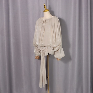 Detail of elegant satin shirt featuring a tied waist bow and luxurious ruffled texture